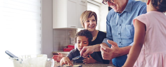 Family caregiver assists her children and her elderly father make cookies during the holidays