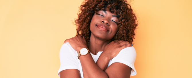 Self-care for caregivers, happy caregiver smiles contently while giving herself a hug