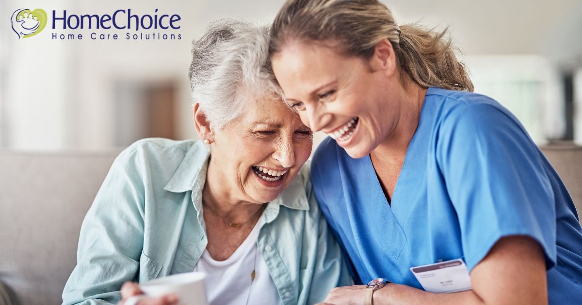 A woman who is providing companion care and her senior client laugh and enjoy their time together.