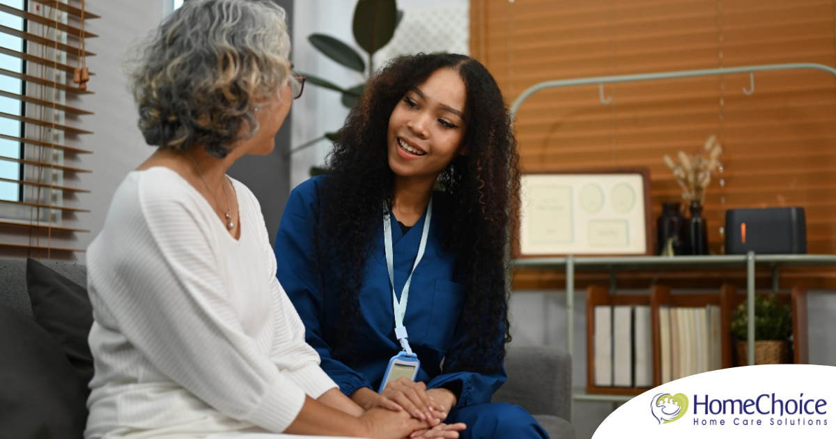 A caregiver patiently and kindly sits down and talks with a senior client, setting a good example for caregivers when it comes to communication.