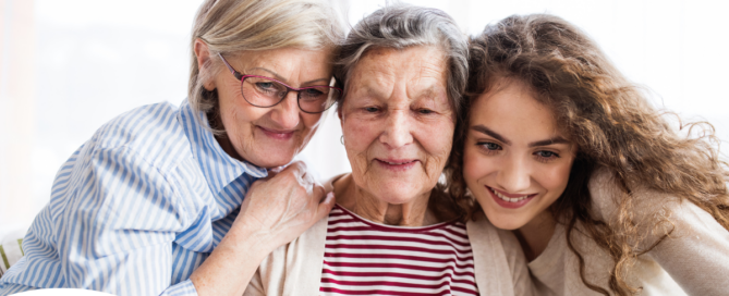 Three generations embrace and look at a computer, representing the sandwich generation.