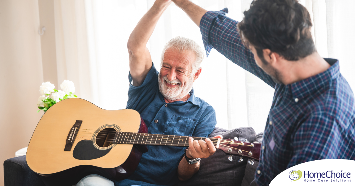 A smiling son high fives his happy elderly father as he plays the guitar, showing the positive effect music can have on people, including those with dementia.