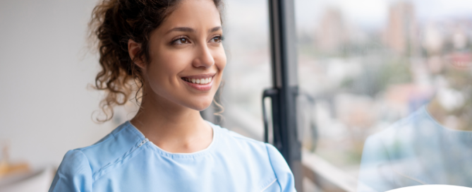 A woman in scrubs smiles, representing the satisfaction that can come with transitioning into a professional caregiving career.