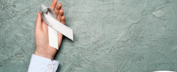 A woman holds a silver ribbon, representing Parkinson’s Awareness Month.