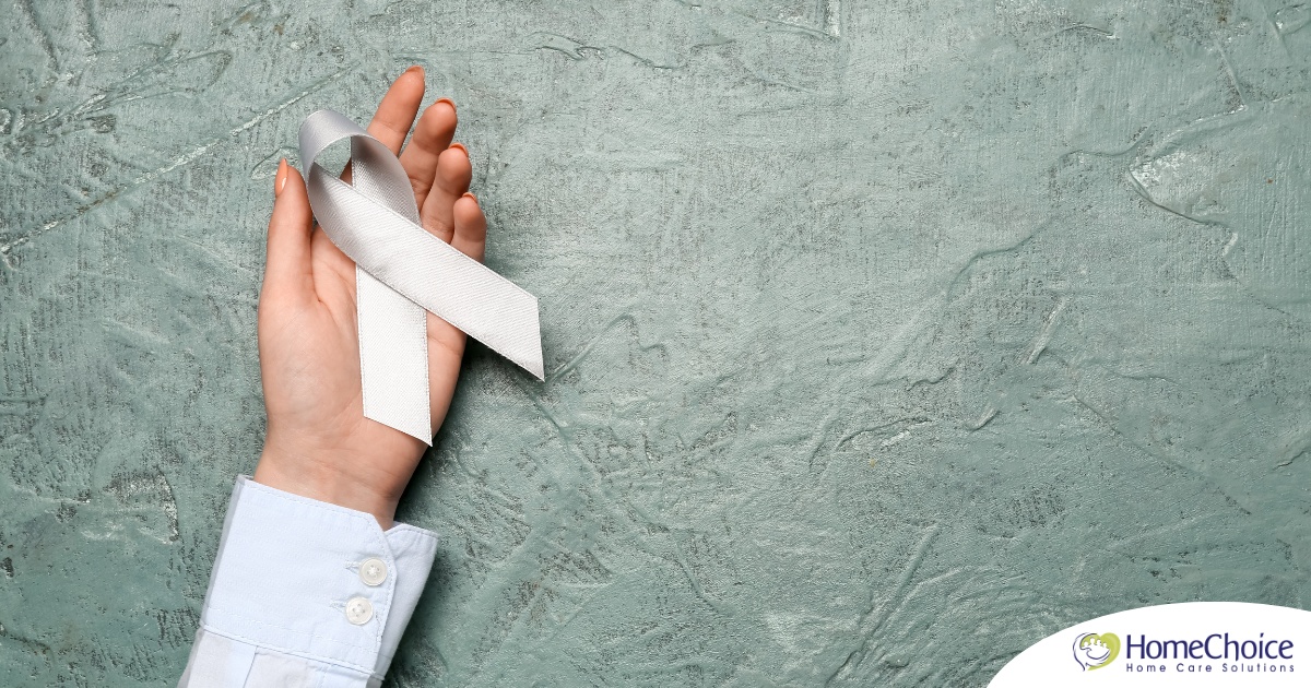 A woman holds a silver ribbon, representing Parkinson’s Awareness Month.