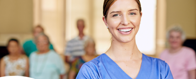 A professional caregiver smiles with seniors behind her, showing how a job with a caregiver agency can be a good choice.