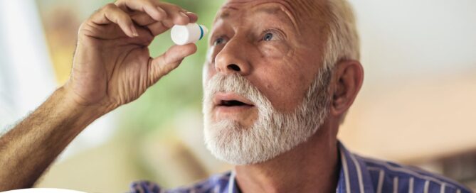 An older man uses eye drops as part of a good care routine to maintain his vision health.