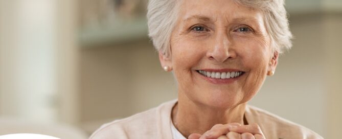 An older woman with healthy teeth smiles, representing good dental hygiene.