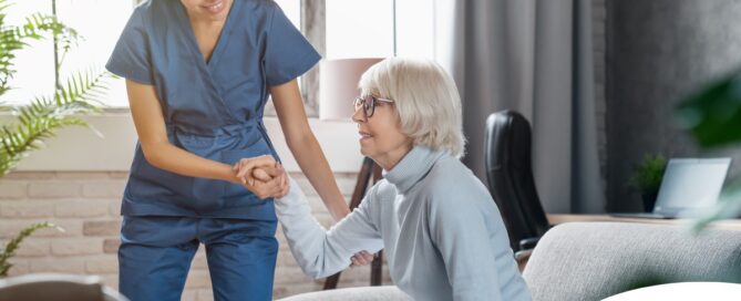 A caregiver demonstrates her caregiver skills by helping an older adult get up.