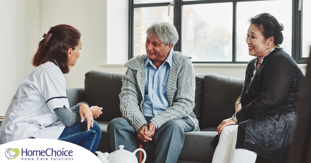 A caregiver talks with an elderly couple representing the kind of communication that professional caregivers need to have to anticipate client needs.