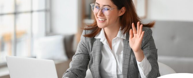 A well-dressed woman smiles and says hi on a videoconference, representing a candidate who is well-prepared for a caregiver interview.