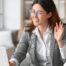 A well-dressed woman smiles and says hi on a videoconference, representing a candidate who is well-prepared for a caregiver interview.