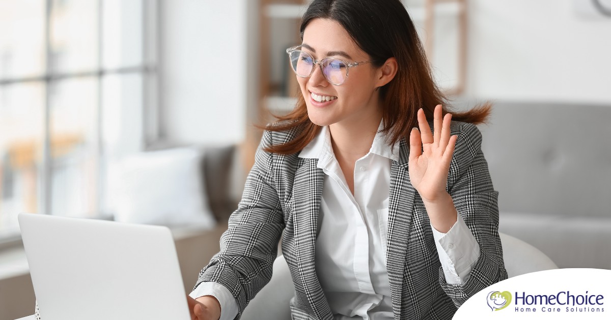 A well-dressed woman smiles and says hi on a videoconference, representing a candidate who is well-prepared for a caregiver interview.