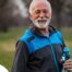 An older man smiles with a water bottle while exercising, representing the benefits of encouraging exercise when caring for seniors at home.