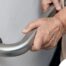 An older adult uses a grab bar representing one of the home modifications that is helpful for fall prevention for elderly adults.
