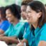 Several students in scrubs happily attend a class, representing caregiver training.