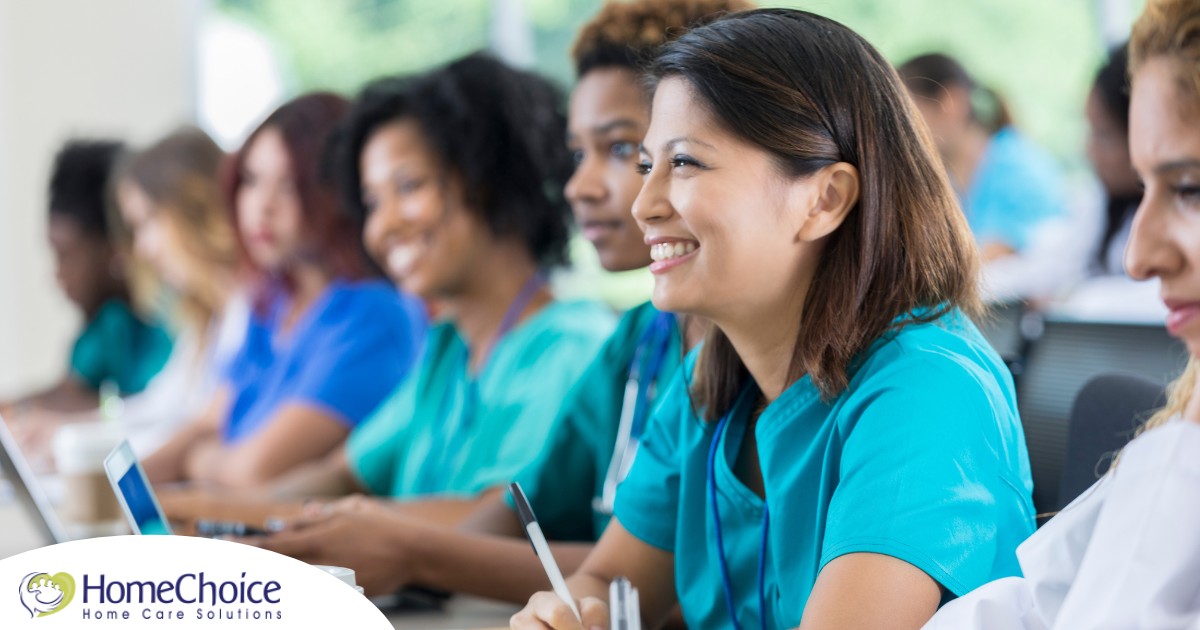 Several students in scrubs happily attend a class, representing caregiver training.