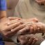 A care provider examines an older adult’s fingers, representing what would happen in an examination for rheumatoid arthritis.