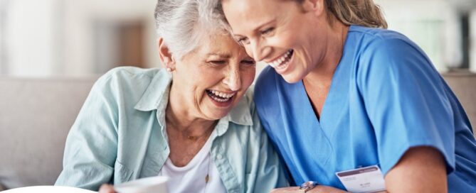A woman in scrubs laughs with a senior woman, representing how caregiving can be a great career choice.