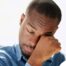 A man tiredly rubs his eyes, representing the exhaustion that can come with family caregiving.