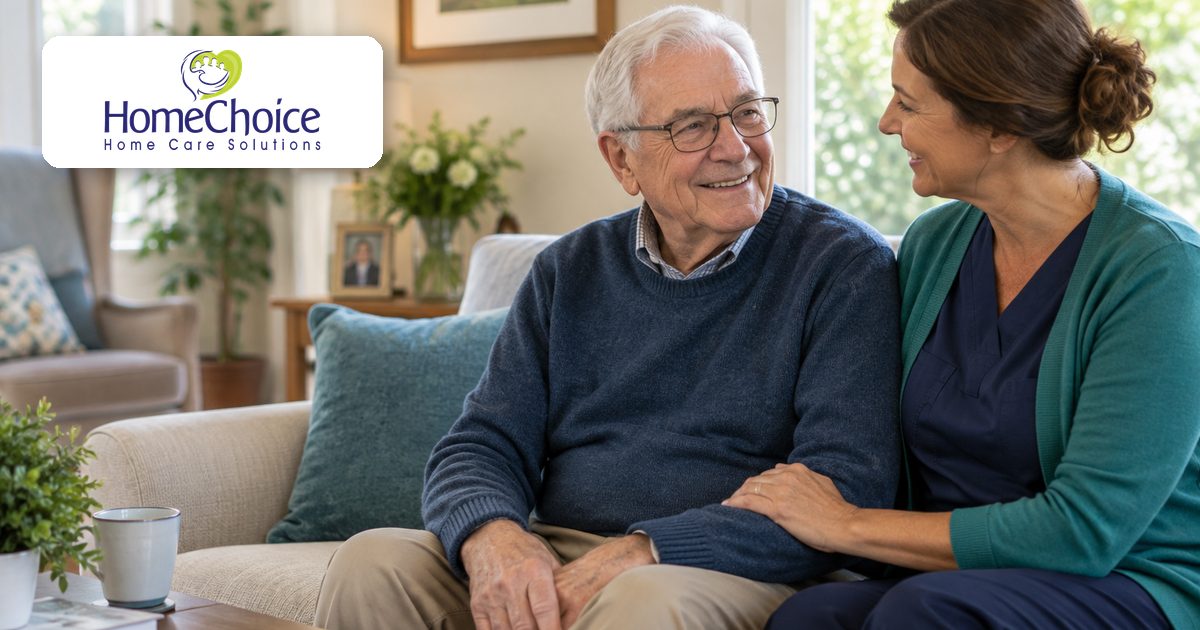 Home caregiver talking with an older man in a bright living room while providing supportive Parkinson’s home care.