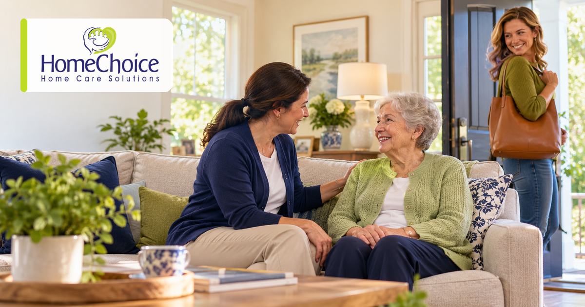 An older woman smiles while talking with a respite caregiver as her adult daughter leaves the home feeling reassured.