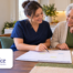 Caregiver in navy scrubs and an older woman smiling together while reviewing a calendar and planning for the holidays at home. The HomeChoice Home Care Solutions logo appears in the lower-left corner.