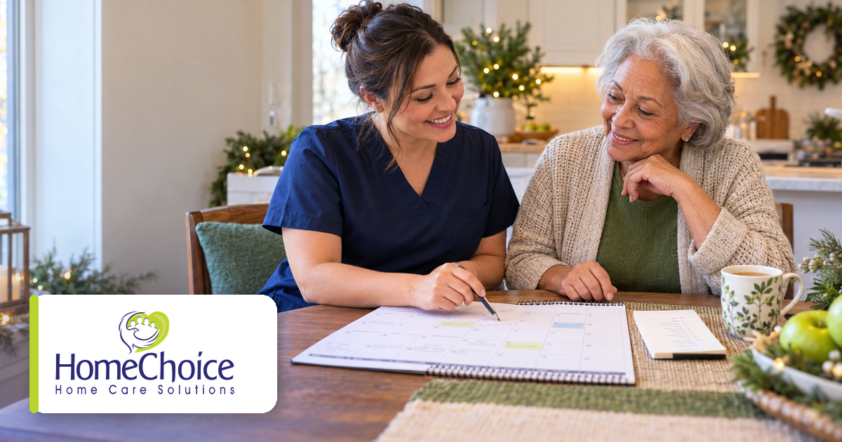 Caregiver in navy scrubs and an older woman smiling together while reviewing a calendar and planning for the holidays at home. The HomeChoice Home Care Solutions logo appears in the lower-left corner.